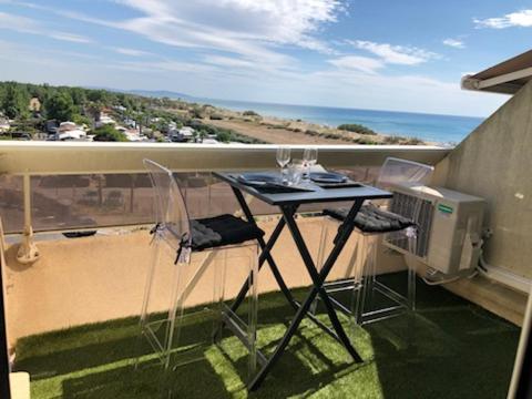 - un balcon avec une table et deux chaises et l'océan dans l'établissement Village Naturiste - Hélio L vue mer, au Cap d'Agde