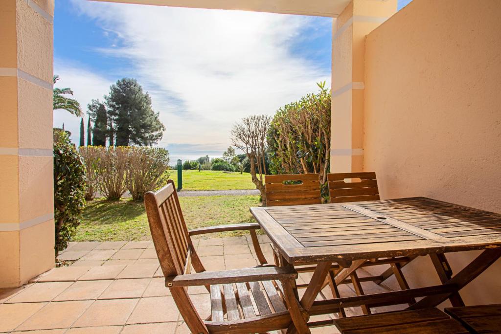 une table et des chaises en bois sur une terrasse dans l'établissement Coté Jardin, Villa de Cap Esterel, à Saint-Raphaël