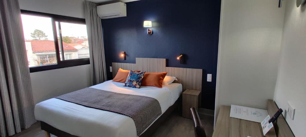 1 dormitorio con 1 cama con pared azul en Logis Hôtel Les Bleuets, en Royan