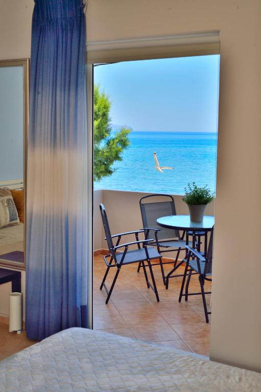a bedroom with a balcony with a table and chairs at Wink Bnb Paraliaki in Kissamos