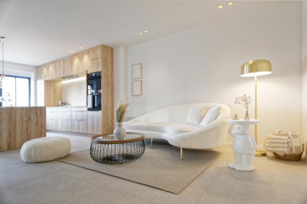 a living room with a white couch and a table at Les Terrasses de Sainte Waudru in Mons