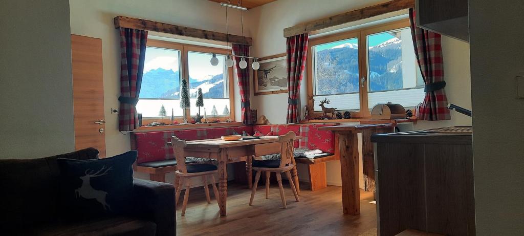 eine Küche mit einem Tisch, Stühlen und Fenstern in der Unterkunft Steinhof in Gries am Brenner