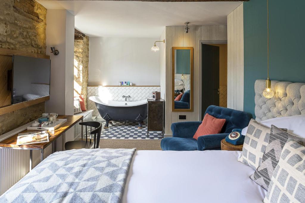 a bedroom with a bed and a bathroom with a tub at The Old Stocks Inn in Stow on the Wold