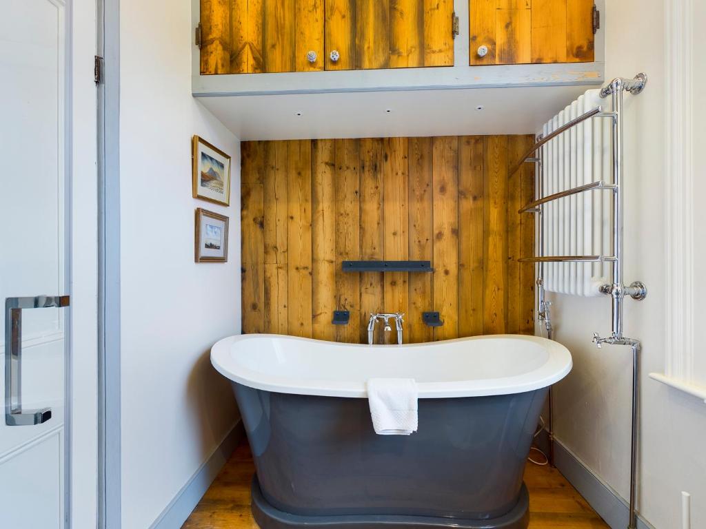 a bath tub in a bathroom with a wooden wall at Ogleforth in York