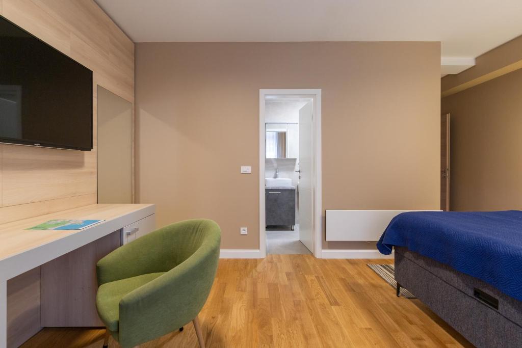 a bedroom with a bed and a chair and a television at Hotel Sky in Zadar