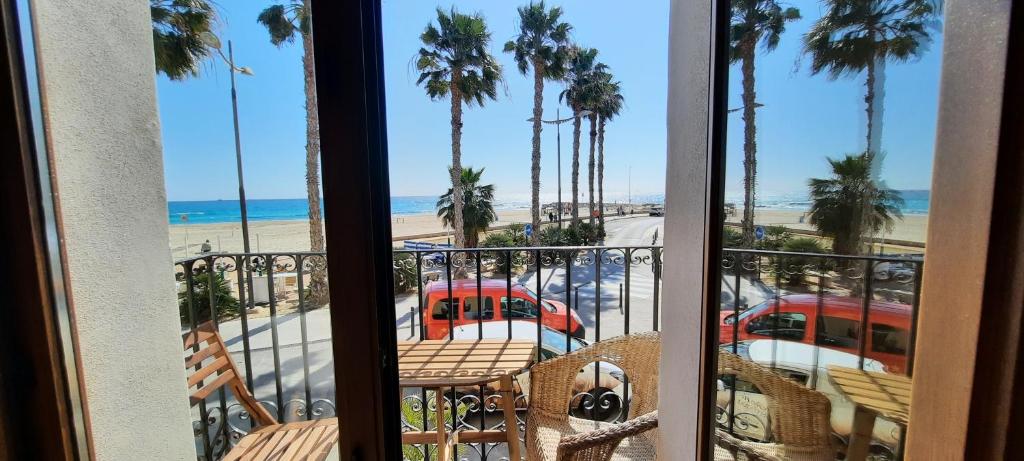 einen Balkon mit Blick auf den Strand und die Palmen in der Unterkunft AR28-1, Coqueto apartamento en primera línea de playa in Villajoyosa