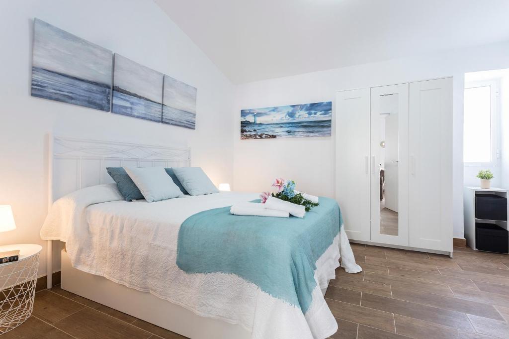 um quarto branco com uma cama com um cobertor azul em San Miguel Terraza Tranquilo Moderno em Jerez de la Frontera