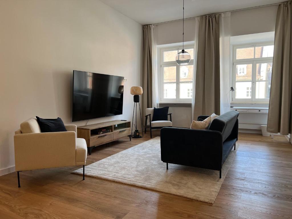 uma sala de estar com sofás e uma televisão de ecrã plano em Maximilianstraße em Augsburg