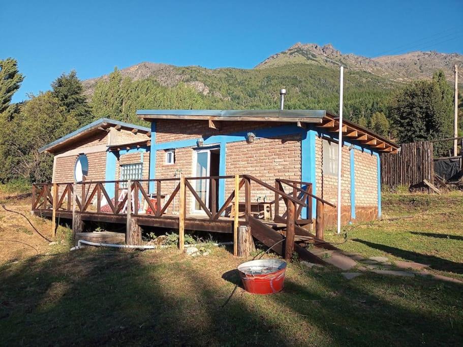 una pequeña casa en un campo con una montaña en Casa de huéspedes La vista en El Hoyo