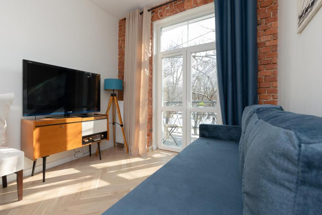 a living room with a blue couch and a television at Warsaw Pruszków Park View Comfortable Apartments by Renters in Pruszków