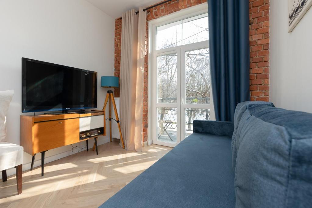 a living room with a blue couch and a television at Warsaw Pruszków Park View Comfortable Apartments by Noclegi Renters in Pruszków