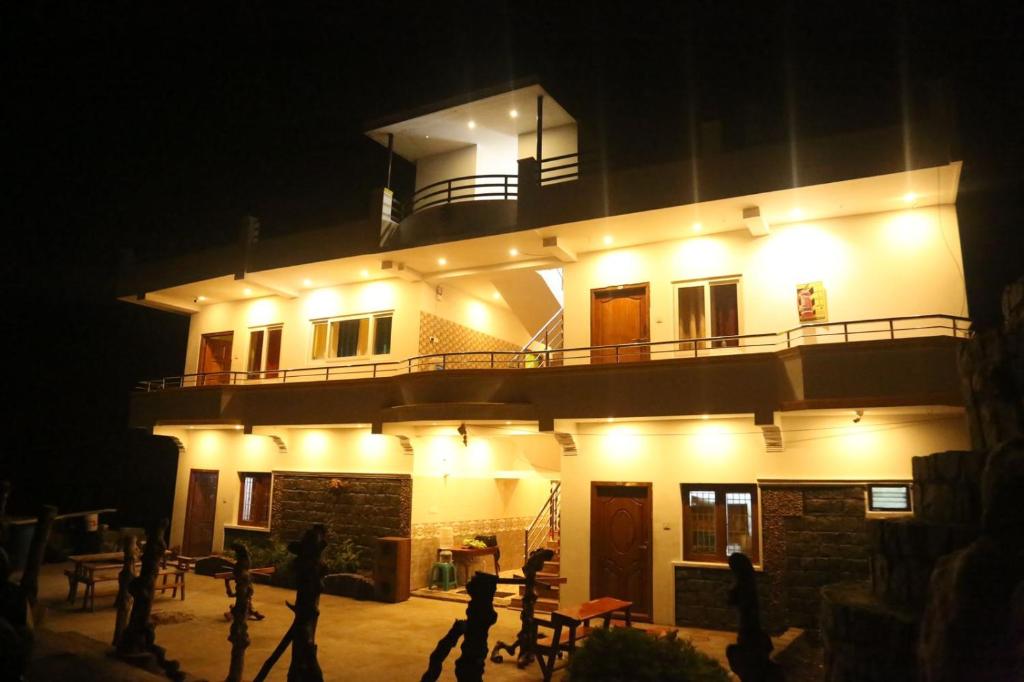 un edificio iluminado por la noche con gente caminando delante en Oneness nest, en Yercaud