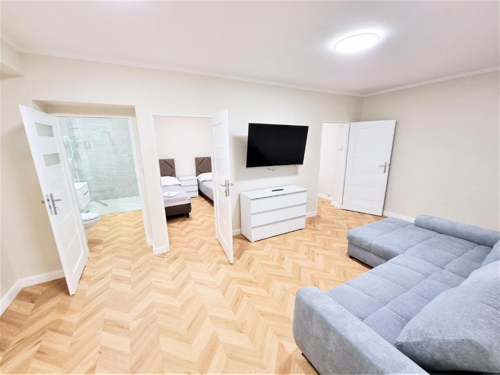 uma sala de estar com um sofá e uma televisão de ecrã plano em Orange Tree Hotel em Będzin
