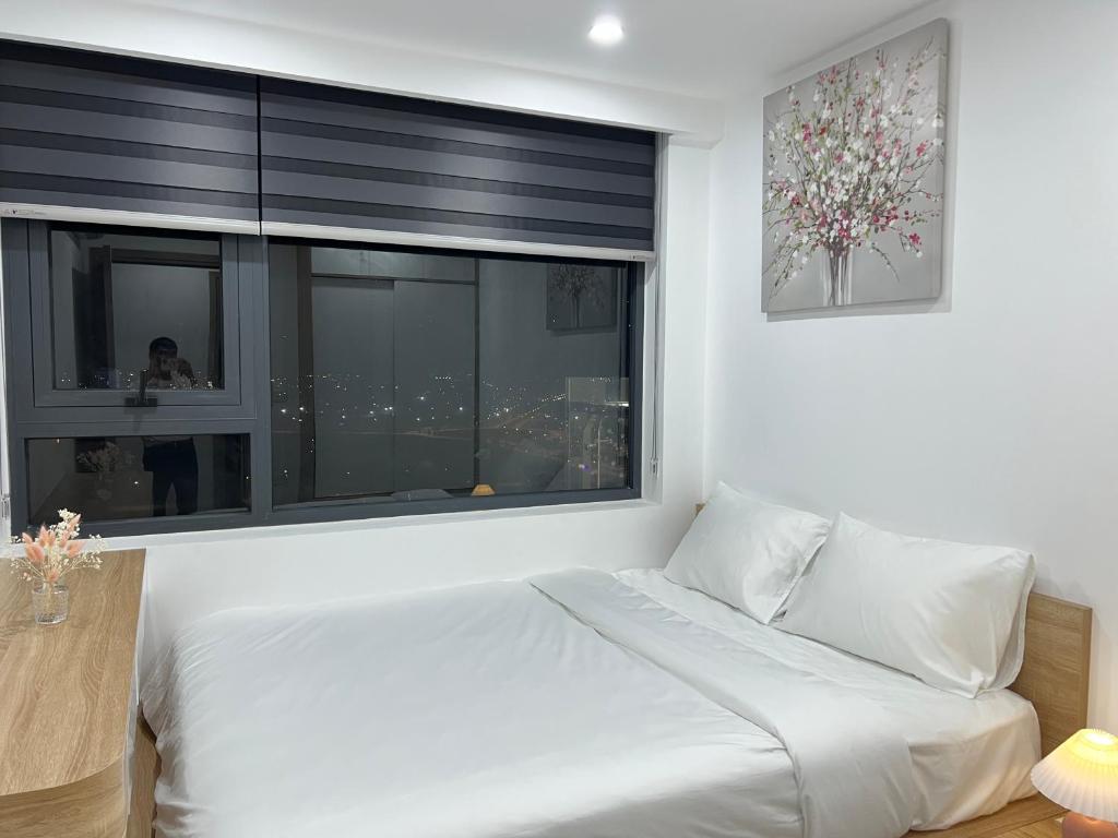 a bedroom with a white bed and a large window at Noric homestay in Hue