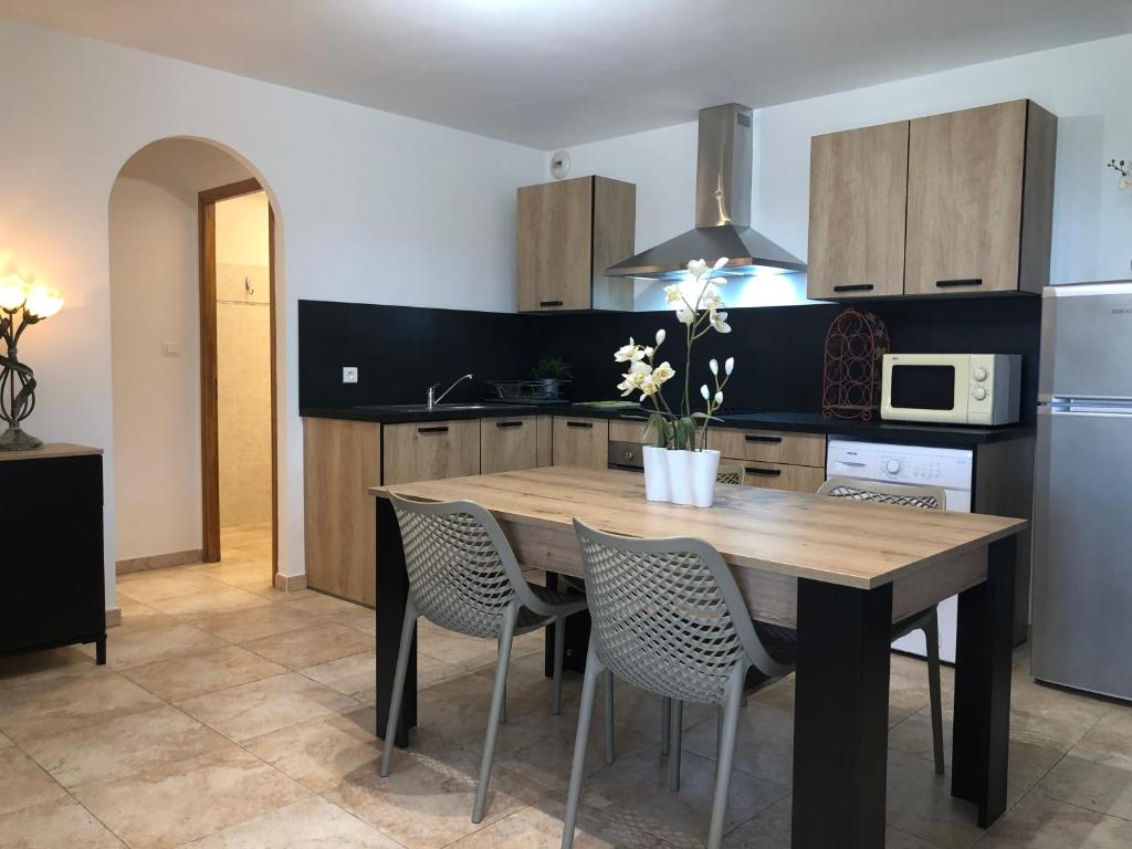 a kitchen with a wooden table with chairs and a refrigerator at Appartement T2 rez de villa in Saint-Florent