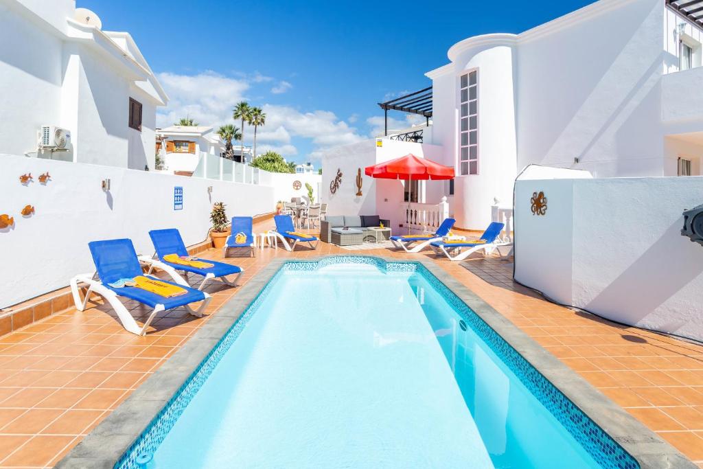 a swimming pool with blue chairs and a swimming pool at Casa Laura in Puerto del Carmen