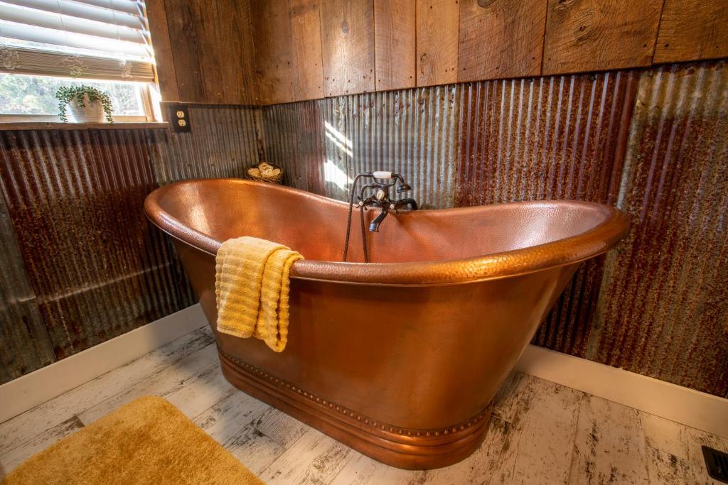 uma banheira de cobre numa casa de banho com paredes de madeira em Nebo's Foot, Cabin Escape with Game-Barn em Dardanelle