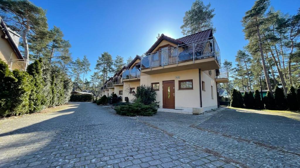 a house on a cobblestone street next to a driveway at Apartament Pobierowo in Pobierowo