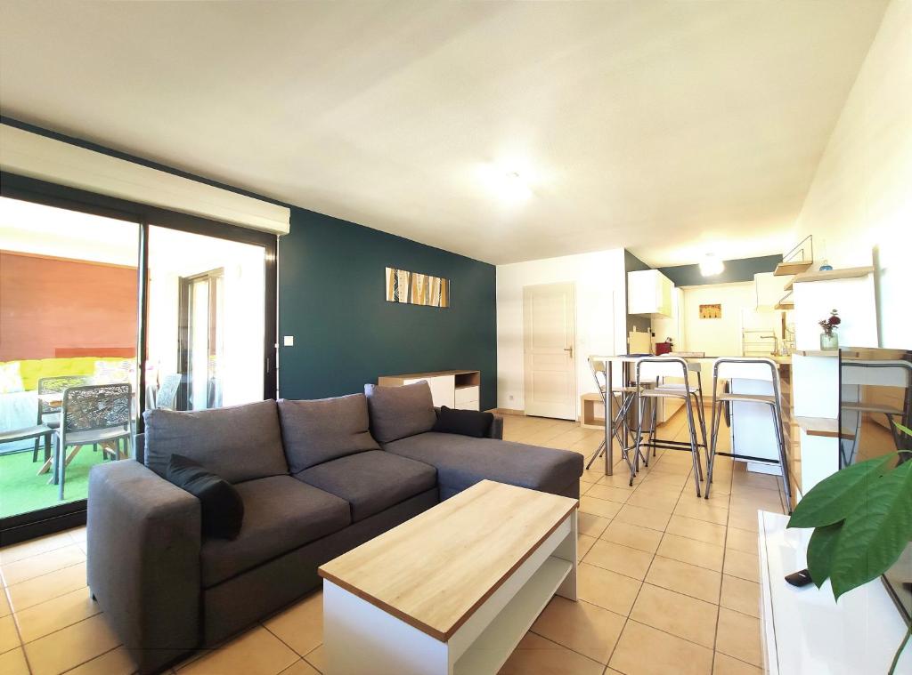 a living room with a couch and a table at Le Dory - Appartement Centre Ville avec Terrasse, Parking & Wifi in Montpellier