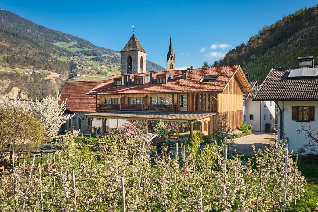 a large wooden building with a church in the background at Kircherhof in Bressanone