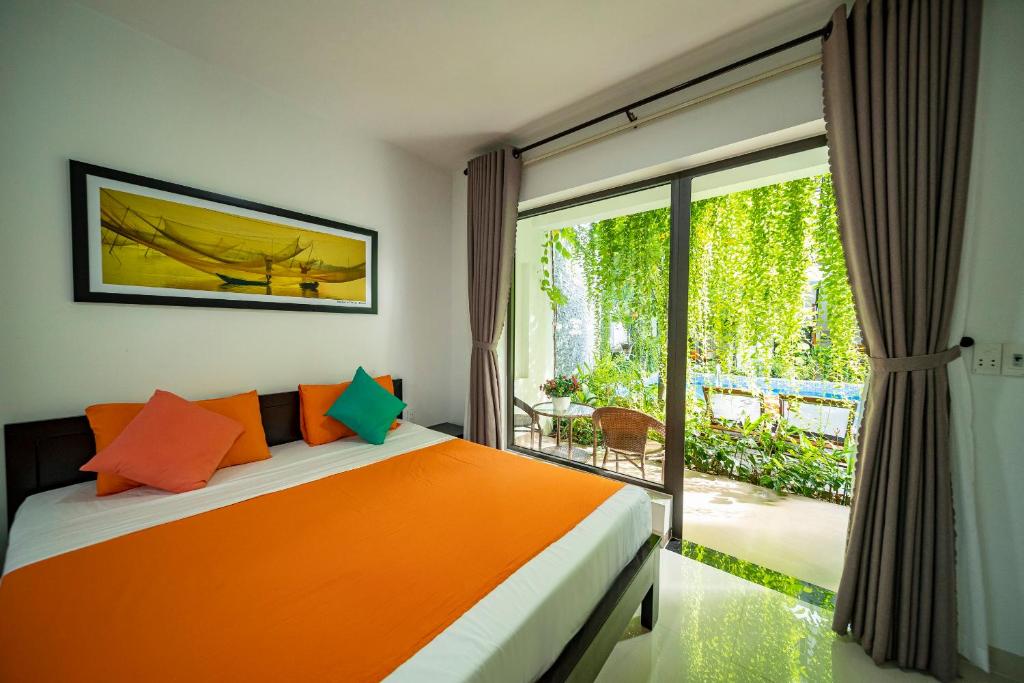 a bedroom with an orange bed and a large window at My Anh Boutique Villa Hoi An in Hoi An