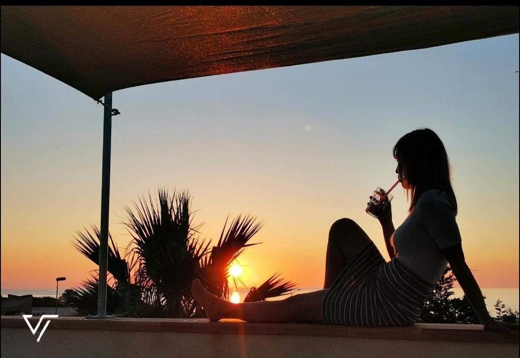 a woman sitting on a ledge looking at the sunset at Villa Tico in Custonaci