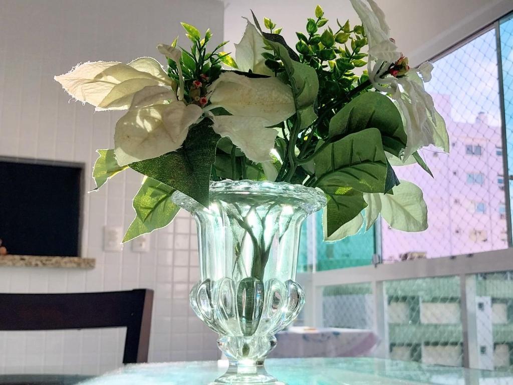 um vaso de vidro com flores sobre uma mesa em Espaçoso aconchegante em Capão da Canoa