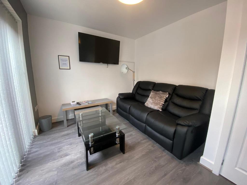 a living room with a black leather couch and a table at Modern holiday home in Greetland