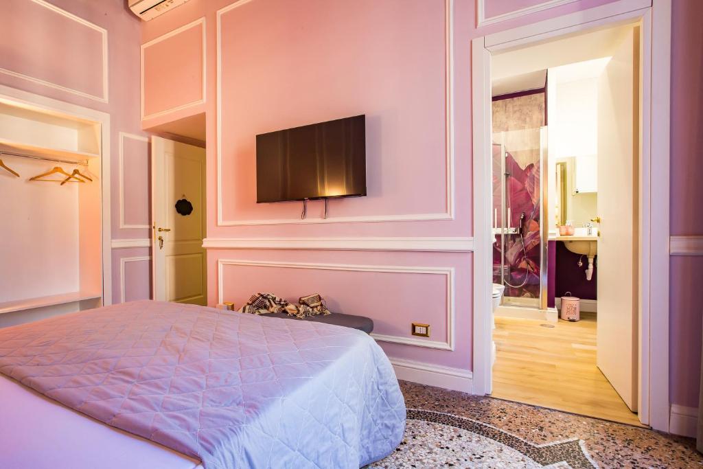 een slaapkamer met een bed en een flatscreen-tv aan de muur bij Hold Rome - Luxury Suites in Rome