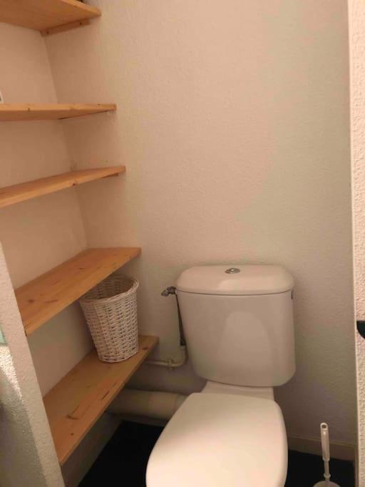 - białą toaletę w łazience z drewnianymi półkami w obiekcie Studio 4 personnes proche des pistes w mieście La Plagne Tarentaise
