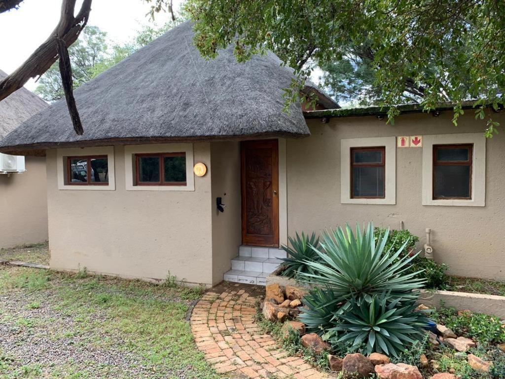 una pequeña casa blanca con techo de paja en Mabalingwe Elephant Lodge 256A, en Moheme