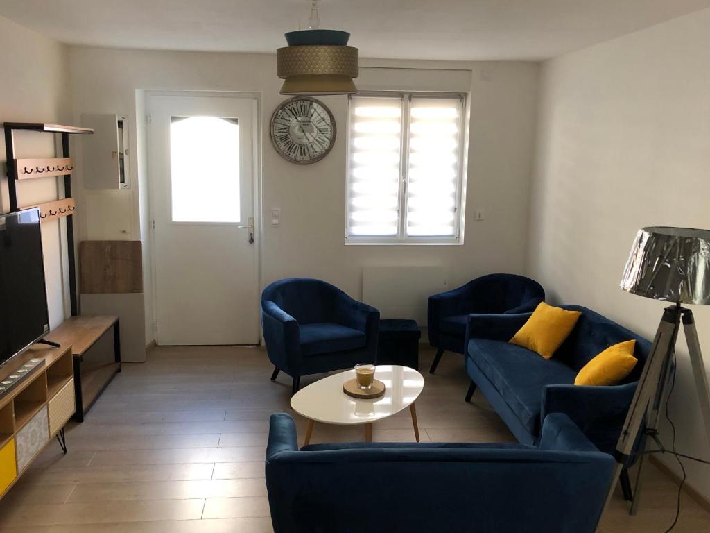 uma sala de estar com cadeiras azuis, uma mesa e um relógio em Une maison agréable pour se détendre em Saint-Quentin