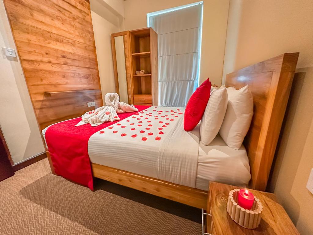 a bedroom with a large bed with red pillows at Emirates Luxury Apartments (Glen Fall Residencies) in Nuwara Eliya