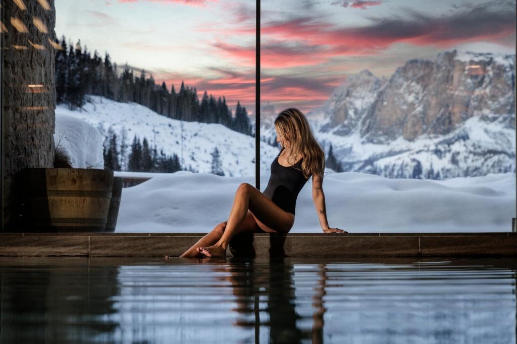 a woman sitting on a ledge in the water at Hotel Costes in Corvara in Badia