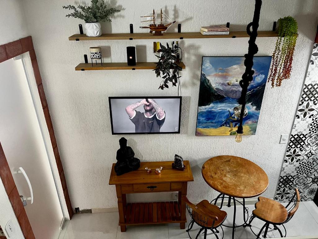 een kamer met een tafel en wat foto's aan de muur bij Meu Loft Geribá em Búzios in Búzios