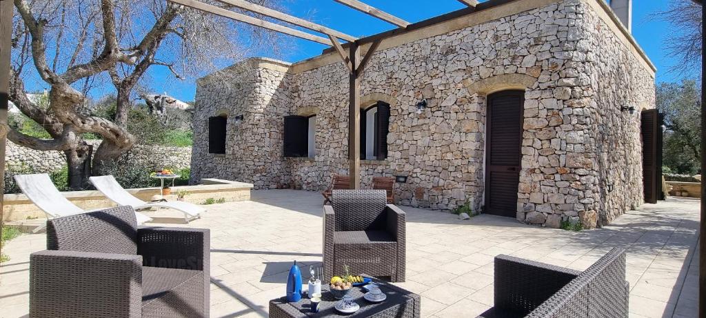 un patio avec des chaises et des tables ainsi qu'un bâtiment en pierre dans l'établissement Stone House Li Turchi 2, à Leuca