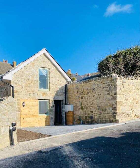 a brick house with a door and a stone wall at Vindelis Cottage Chesil Beach in Portland