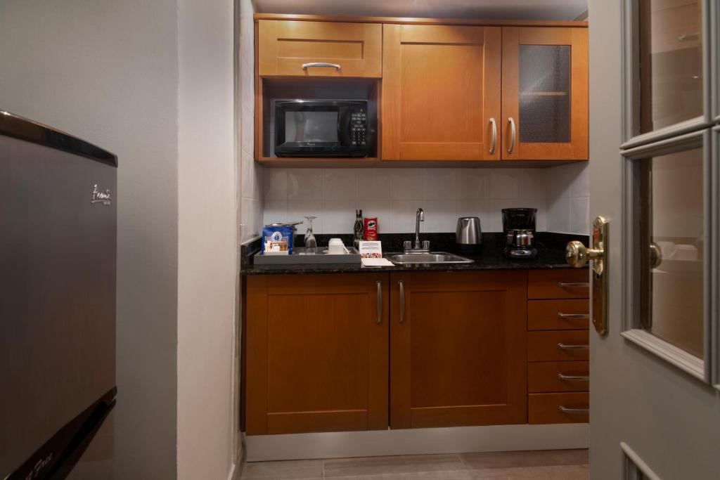 a small kitchen with wooden cabinets and a microwave at Catalonia Santo Domingo in Santo Domingo