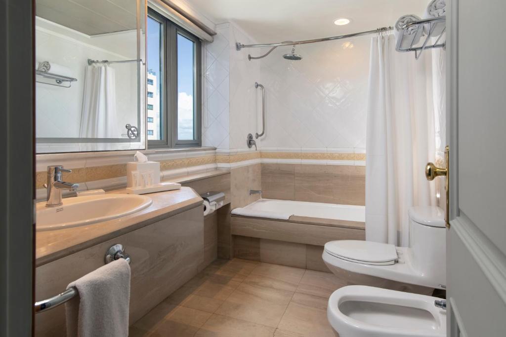 a bathroom with a tub and a toilet and a sink at Catalonia Santo Domingo in Santo Domingo