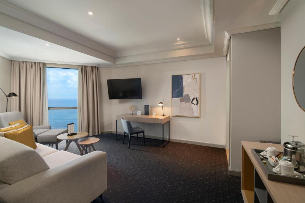a hotel room with a couch and a table and a desk at Catalonia Santo Domingo in Santo Domingo
