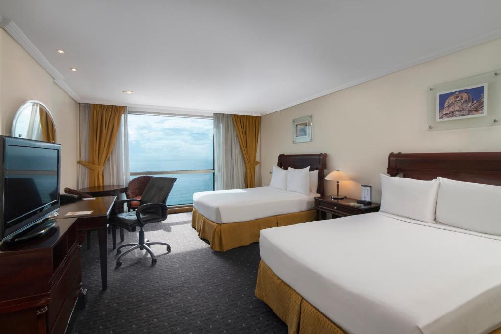 a hotel room with two beds and a flat screen tv at Catalonia Santo Domingo in Santo Domingo