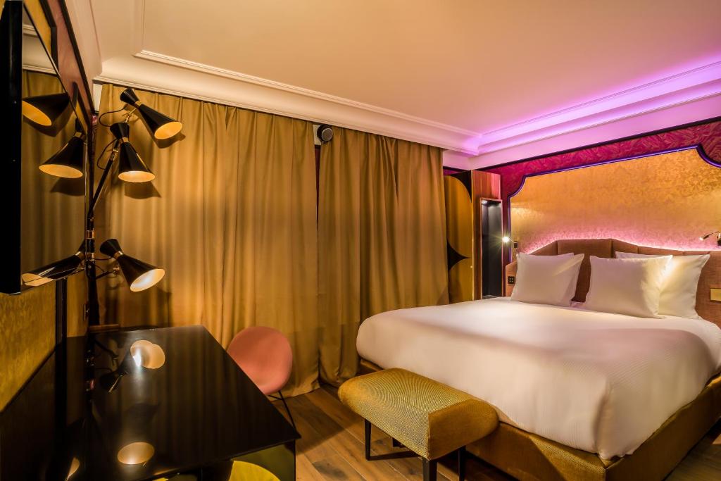 a hotel room with a large bed and a chair at Idol Hotel in Paris