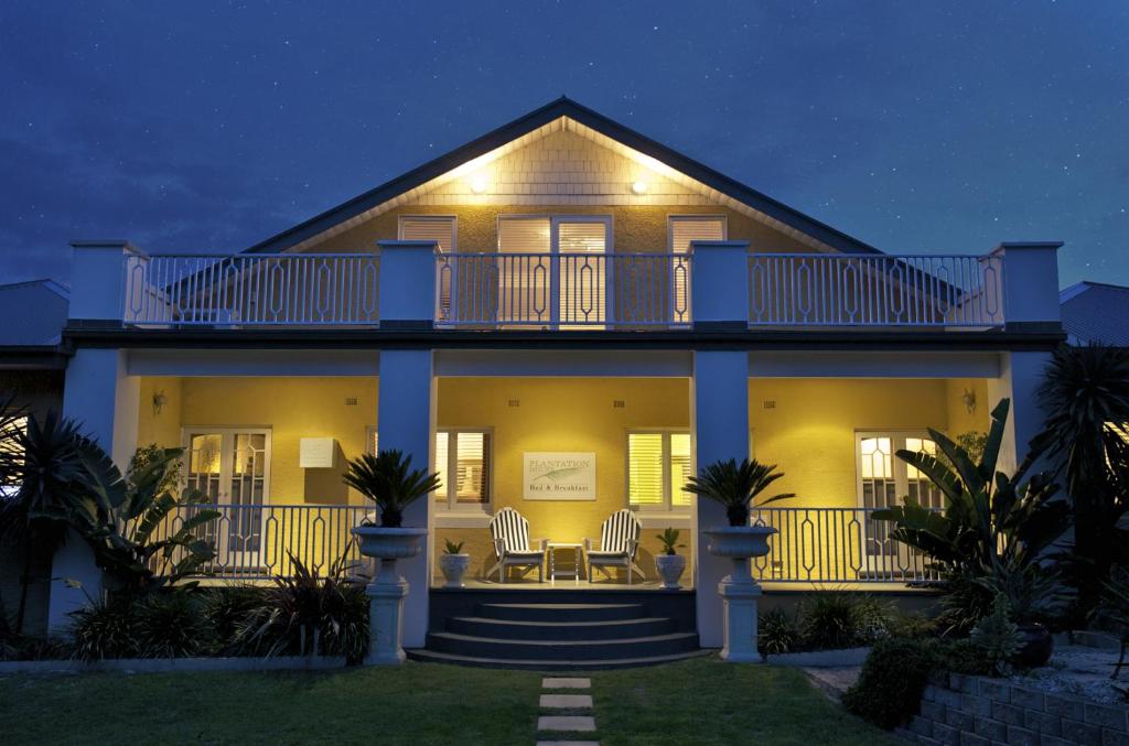 Cette grande maison blanche dispose d'un balcon la nuit. dans l'établissement Plantation House at Whitecliffs Bed and Breakfast, à Rye