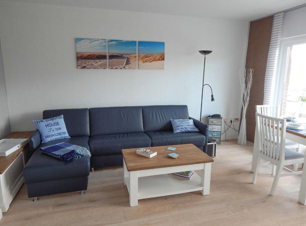 uma sala de estar com um sofá azul e uma mesa em App. Saal em Wenningstedt