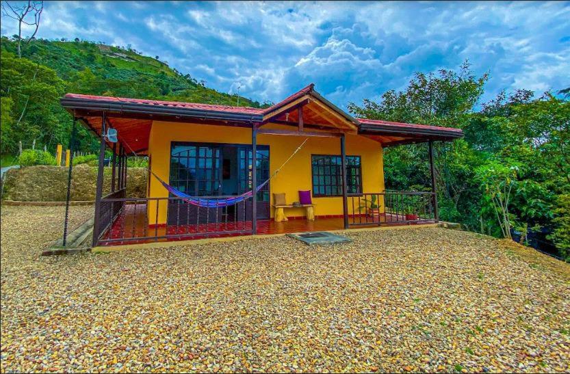 une petite maison jaune et rouge avec une terrasse couverte dans l'établissement Casas De Campo - El Paraíso, à La Vega