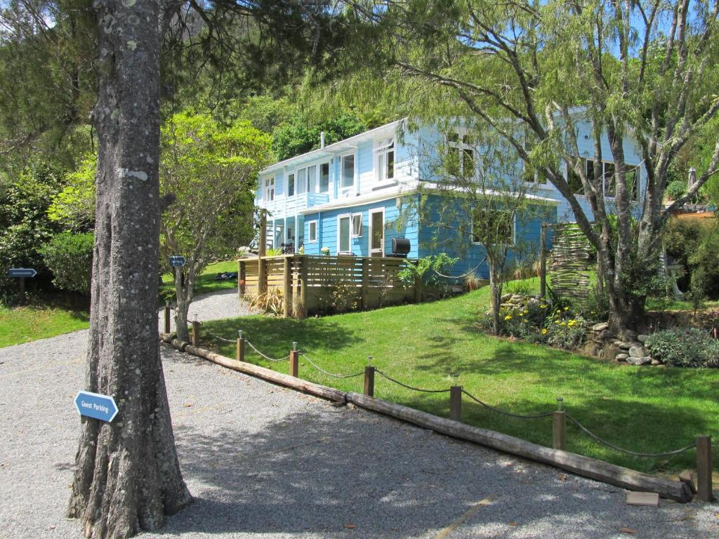 a blue house with a sign on a tree at Anakiwa 401 in Anakiwa