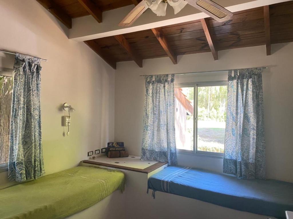 Habitación con 2 camas y ventana con cortinas. en Playa Tapitos en Tigre