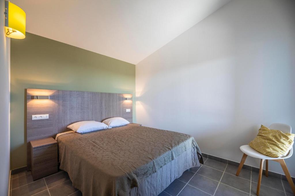 a bedroom with a bed and a table and a chair at Résidence Santa Monica in Bonifacio