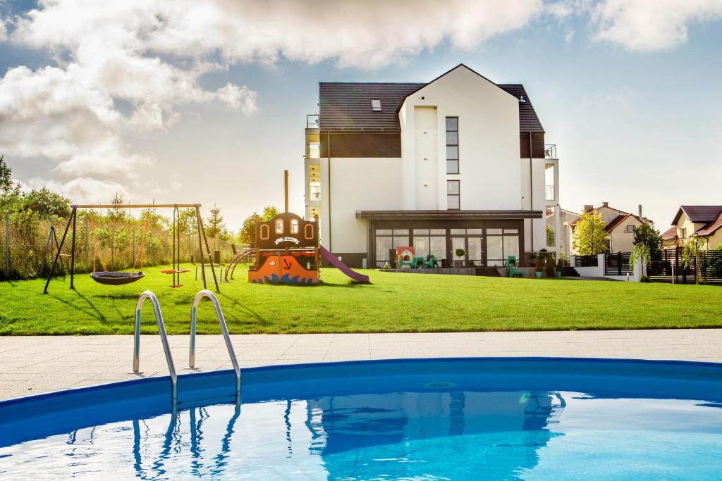 a house with a pool and a playground at Apartamenty Rodzinne Plater74 in Darłówko