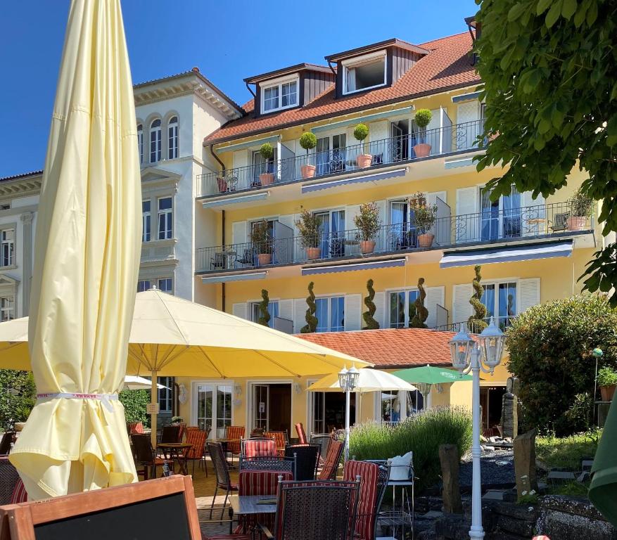 um edifício amarelo com mesas e cadeiras e um guarda-sol em Seehotel Schäpfle em Überlingen